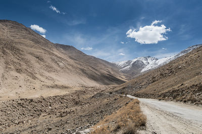 Scenic view of road by mountains against sky