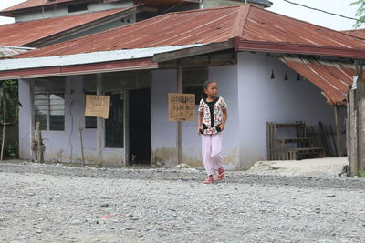 Girl walking against house in town