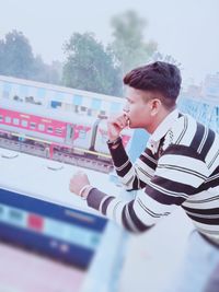 Side view of young man looking at camera