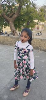 Portrait of cute girl standing against trees