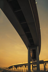 Low angle view of elevated road against sky at sunset