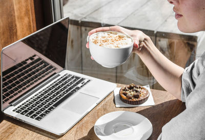 Midsection of man using laptop on table