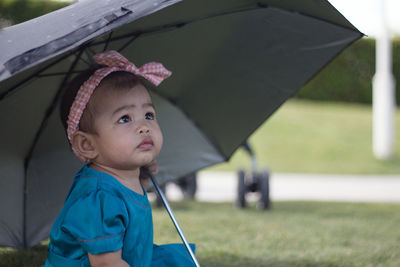 Close-up of innocent baby girl holding umbrella on field