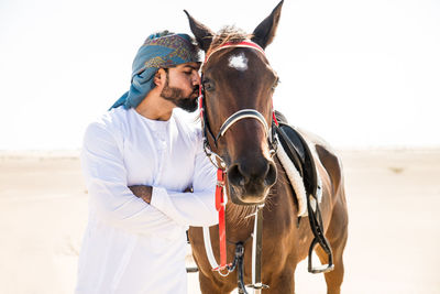 Man kissing horse in desert against sky