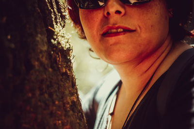 Close-up portrait of mid adult man on tree trunk