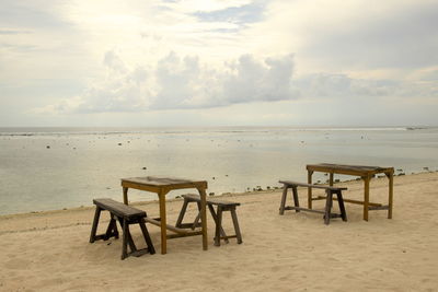 Chairs and table on beach against sky