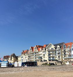 Houses by buildings against blue sky