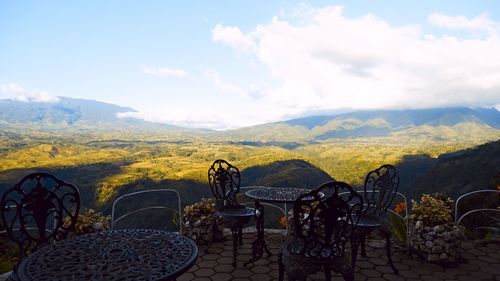 Empty chairs and tables against sky