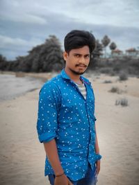 Portrait of young man standing at beach