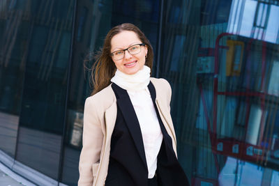 Portrait of a happy successful woman with glasses on the background of an office building