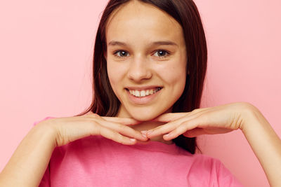 Portrait of young woman against pink background