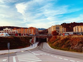 Road by buildings against sky in city