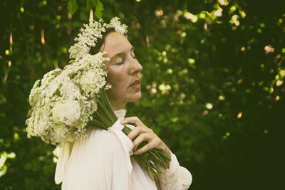 Woman in white blouse with flower bouquet and headband vii