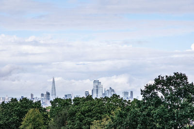 View of trees and buildings against cloudy sky