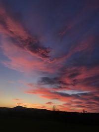 Silhouette landscape against dramatic sky during sunset