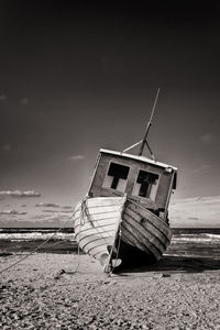 Abandoned ship moored on beach against sky