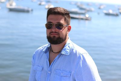 Portrait of smiling young man wearing sunglasses standing at beach