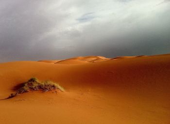 Scenic view of desert against cloudy sky