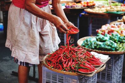 Man holding red chilies at market stall