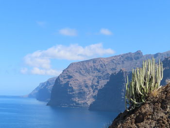 Scenic view of sea and mountains against blue sky