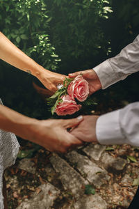 Cropped hand of couple holding hand against plant