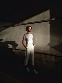 Portrait of young woman standing against wall