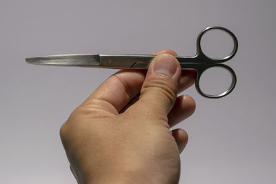 Close-up of hand holding metal against white background