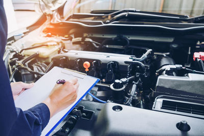 Cropped hands of mechanic repairing car in garage