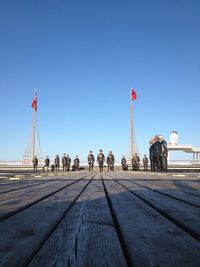 People at beach against clear blue sky