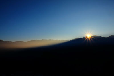 Scenic view of silhouette mountains against clear sky during sunset