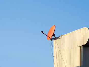 Red satellite dish hangking on roof top of building