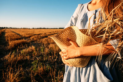 Ukrainian woman in blue linen dress with wheat spikelets on wheat fields. war in ukraine threatens