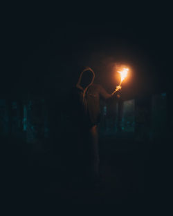 Rear view of woman standing on street at night