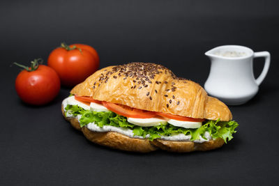 Vegetarian croissant with tomato cheese and salad on a black background