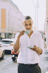 Portrait of businessman drinking coffee on sidewalk cafe in city