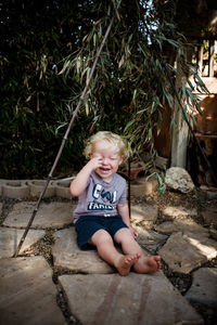 Portrait of happy boy sitting on stone