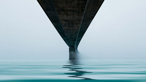 Low angle view of bridge over sea against clear sky