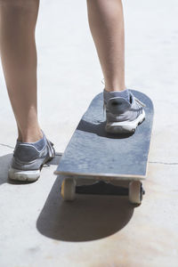 Low section of woman with skateboard standing on road