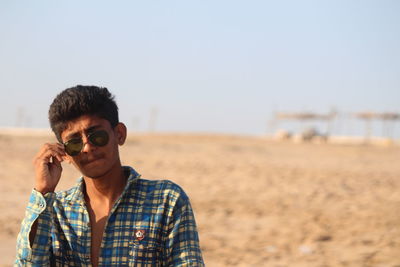 Portrait of young man wearing sunglasses against sky