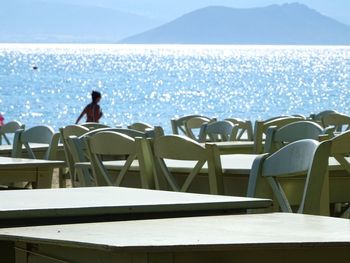 People on chair by sea against sky