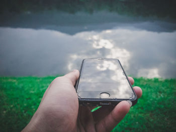 Midsection of person holding smart phone against sky