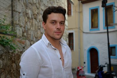 Portrait of young man standing against brick wall