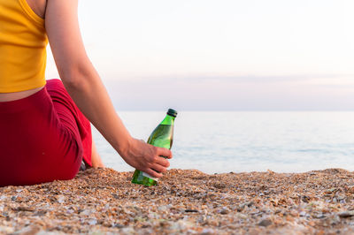 Midsection of woman using mobile phone at beach