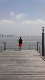 Rear view of woman standing on pier