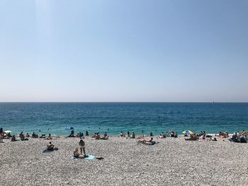 Group of people on beach against clear sky