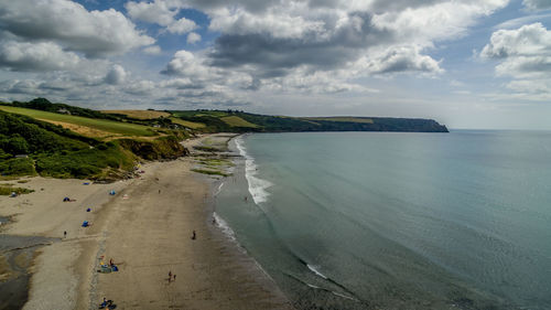 View of calm beach against cloudy sky