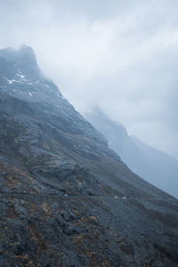 Rocky cliffside with cloudy tops and road. vertical. long shot.