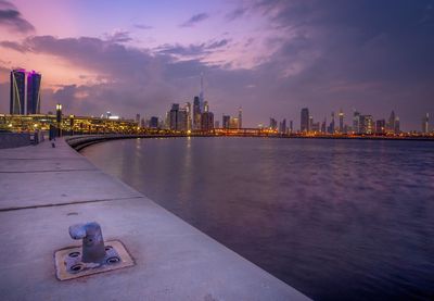 City by river and buildings against sky