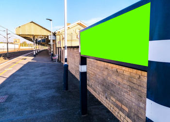 Footpath by building against clear blue sky