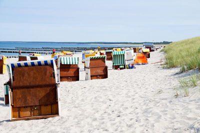 Hooded chairs on sand against sea at beach